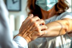 Doctor examines a patient's arm, likely checking for a rash or skin condition. Healthcare professional interaction, medical examination, close-up view, clinical setting, focus on diagnosis.