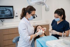 Dentist and assistant performing dental treatment on a patient in a modern clinic.