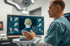 Doctor in scrubs examines a medical scan on a monitor in a modern hospital setting. Focus on diagnostics and healthcare technology. Blue and white color scheme.