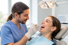 Dentist examines patient's smile in a bright clinic, highlighting dental evaluation for cosmetic and functional care.