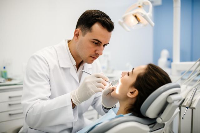 Dentist closely examining a patient's teeth in a bright dental clinic during a routine exam.