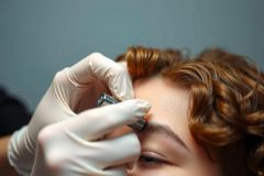 Close-up of a beauty treatment, with a tool held by a hand in a white glove. Focus on the eye and facial area. Professional beauty service.