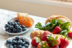 A vibrant breakfast still life featuring blueberries, strawberries, and a croissant on a white plate, set against a bright, sunny backdrop. Fresh, colorful, and delicious morning treats.