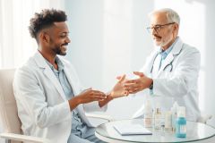 Two doctors in white coats shaking hands in a bright, modern medical office. A table displays skincare products. Represents healthcare consultation, collaboration, and potentially dermatology or cosmetic procedures. Clean, professional environment with light blue and white tones.