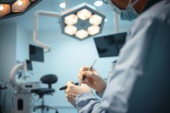 Surgical scene: A surgeon in gloves holds a scalpel in a brightly lit operating room. Focus on precision and medical tools. Healthcare, surgery, medical procedure.