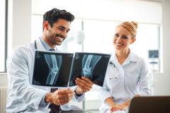 Doctors examining an X-ray in a medical setting. Two healthcare professionals review a patient's bone scan, highlighting diagnostic assessment and medical consultation.