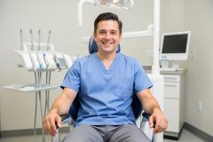 Smiling dental professional seated in an exam chair, ready to discuss treatment continuity and next steps with a patient.
