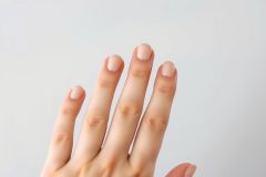 Close-up of a hand against a plain background. The hand appears clean and healthy, with neatly trimmed nails. The image has a minimalist aesthetic and soft lighting.