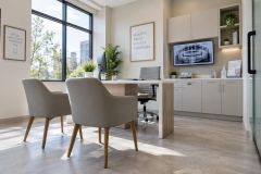 Modern dental consultation room with chairs, desk, panoramic dental X-ray on screen.