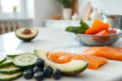 Healthy breakfast still life featuring avocado slices, blueberries, cucumber, and salmon on a marble surface. Fresh, vibrant colors and a clean aesthetic convey wellness and nutrition.