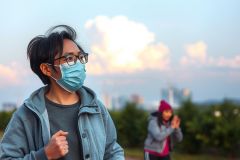 The image depicts an individual wearing a protective face mask, suggesting they may be in a public place or during a time when such precautions are necessary. 