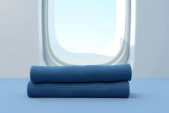 Blue towels neatly stacked against a bright, blurred background resembling a window view. Focus on texture and calming colors. Minimalist still life photography.