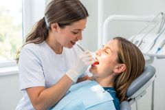 Dentist examines a patient's teeth and gums with a mirror during a routine dental check.