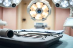 Surgical instruments on a tray in an operating room. Focus on medical tools, sterile environment, and bright lights. Healthcare, surgery, and medical equipment theme.