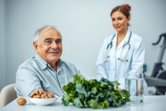 Senior man with a doctor in the background, focused on healthy eating. The scene includes fresh kale, nuts, and an egg, promoting wellness and nutrition. Light blue and green tones create a calm, medical setting. Healthy lifestyle, senior care, and doctor consultation themes.