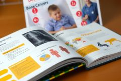 The image displays an open book or magazine with a cover featuring a child and text about bone cancer. The spine of the book shows additional information on bone health and medical conditions.