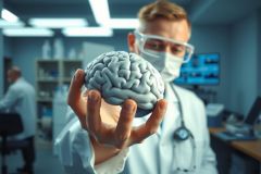 Scientist in lab coat holds a 3D model of a human brain. Research, medical science, neuroscience, and anatomy themes are represented. Blue and white color scheme, lab environment.