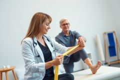 Physical therapist examining patient's leg with a measuring tool in a clinic setting. Healthcare professional, examination, rehabilitation, medical, wellness, patient care.