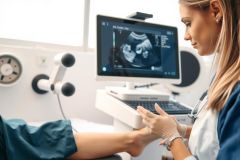 Ultrasound scan in progress. Healthcare professional examining a patient using an ultrasound machine, likely for prenatal or diagnostic purposes. Focus on medical technology and patient care.