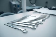 Surgical instruments laid out on a sterile medical surface. Close-up view of metallic tools in a clean, clinical environment. Focus on precision and healthcare.