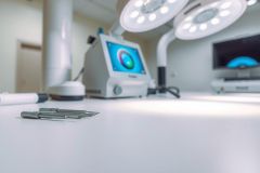 Surgical instruments on a sterile white table in an operating room. Includes a surgical retractor, light source, and monitor, highlighting the clean and clinical environment. 