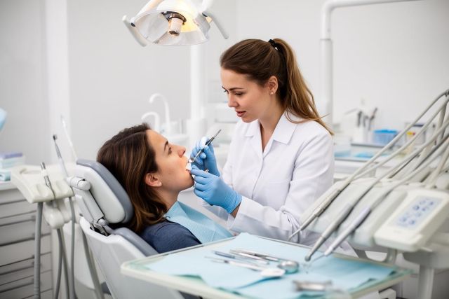 Dentist examines patient's mouth during a dental consultation in a modern operatory.
