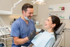 Orthodontist smiling as a patient with braces reclines in the dental chair for a routine check-up.