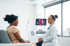 Doctor consults with patient in a modern medical office. Focus on healthcare, examination, and professional medical setting. Warm, bright colors create a welcoming atmosphere.