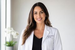 Smiling cosmetic medicine specialist in white coat in a calm clinic portrait.