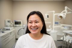 Smiling adult patient seated in a dental exam chair showing braces, illustrating adult orthodontic treatment.