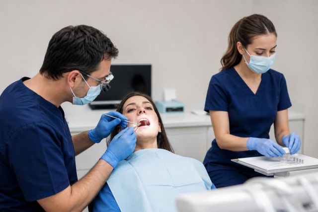 Dentist and assistant examining patient in modern dental clinic, clinical consultation and treatment setting.