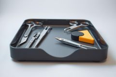 Surgical instruments, including forceps and scissors, are displayed in a gray medical tray alongside black and yellow sponges. A close-up view showcases the tools' metallic sheen and sterile environment.