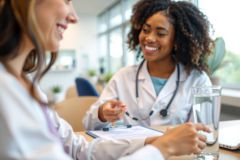 Doctor consulting with a patient, wearing a white coat and stethoscope. Medical examination in a bright, modern office setting. Focus on healthcare and patient care.