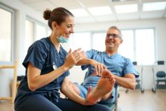A healthcare professional in scrubs examines a patient's foot during a check-up in a medical office setting. Focus on foot care and patient wellness.