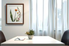 Modern office workspace with a white table, potted plant, notepad, pen, and botanical print artwork. Bright, clean environment featuring neutral colors and natural light.