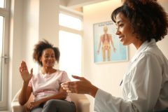 Doctor consulting with patient in a bright office. Healthcare professional discusses health concerns, showcasing a friendly and supportive medical environment. Focus on patient care and well-being.