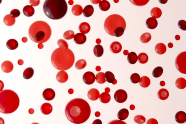 The image consists of numerous small red spheres dispersed across a neutral, possibly grey background. The spheres vary in size and are closely packed together, creating a dense pattern that covers the entirety of the image.