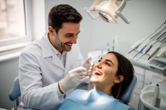 Dentist examining a patient's teeth under a dental light during a cosmetic dental assessment.