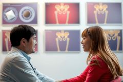 Two people, possibly a doctor and a patient or an expert and a customer, are engaged in a discussion within a medical office setting.